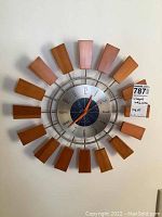 Full view of Wingard sunburst wall clock with 18 wooden blocks and metal frame, showing the clock face and orange hands.