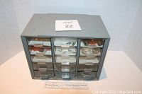 Full front view of gray plastic 15-drawer storage cabinet showing all drawers closed and visible contents inside the transparent drawers.