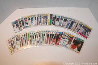Two rows of 64 1983/84 OPC hockey card singles in plastic sleeves shown spread out on a white surface.