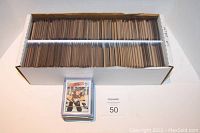 Long cardboard box filled with 1988/89 Topps hockey cards arranged in rows. A separate stack of sleeved and top loaded cards placed in front of the box.
