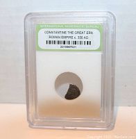 Frontal view of slabbed coin labeled with era and registry number