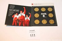 Image showing black presentation folder opened, holding 8 gold-toned NHL coins for Salt Lake 2002 Olympics, and displaying Olympic team celebration photo on inner left side.