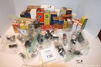 Photo showing a large assortment of loose radio tubes in clear plastic bags along with multiple original vintage cardboard boxes of various brands and types.