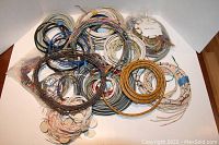 Multiple coils of copper wire in various colors and gauges, some bundled with tape or plastic ties shown in a white box.
