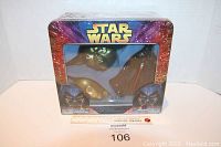 Front view of sealed Star Wars metal tin gift set with three glass ornaments visible (C-3PO, Darth Vader, Yoda) inside.