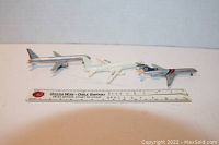 Three model airplanes arranged next to a ruler showing scale; includes Flying Tigers Boeing 727, American Airlines Boeing 757, and a Delta Airlines TriStar model.