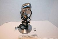 Front view of the vintage Electro Voice microphone mounted on a round metal base with the cable coiled around the stand.