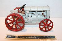 Left side view of vintage Ertl Fordson cast iron tractor alongside ruler for scale.