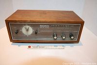 Front view of the Sony AM radio showing clock, tuning dial, knobs, and toggle switches with ruler for scale