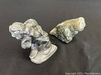 Two Inuit stone carvings shown side by side on black background, highlighting size and shape difference.