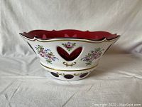Side view of vintage Bohemian ruby glass bowl with white overlay featuring floral decoration and gold accents.