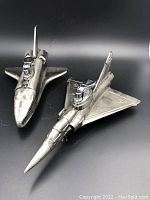 Photo showing both lighters side by side, aircraft shaped, metal finish, ignition mechanisms on top