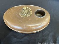 Top view of the oval copper bed warmer showing the brass cap with ring and circular cup holder beside it, surface shows wear and patina.