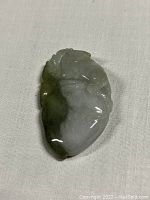 Front view of the carved jade pendant showing detailed shape and coloration