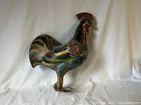 Full view of rooster figurine showing profile stance and enamel work