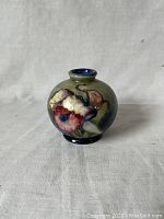 Front view showing colorful hand-painted floral design on squat vase