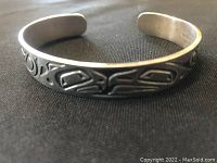 Front angled view showing the First Nations style engraved motifs on sterling silver cuff bracelet.