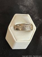 Front view of sterling silver ring on white display stand showing whale motif.