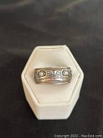 Front view of the sterling silver ring displayed on white ring holder showing the whale motif engraving