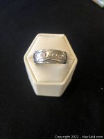 Front view of silver men's ring with First Nations whale design on white ring stand