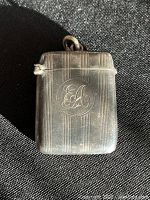 Front view of the sterling silver match vesta showing monogram EA and vertical lines design.