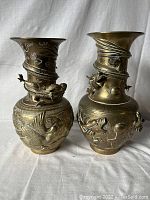 Two large bronze vases with dragons spiraling around the necks, detailed relief on bodies showing fish and dragon motifs.