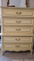 Photo shows front view of yellow 5 drawer chest with gold trim and ornate gold drawer handles.