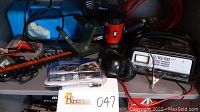 Photo shows electric hedge trimmer and miscellaneous tools including lantern, battery charger, fan, and cords.