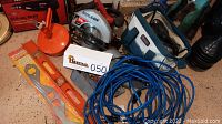 Full lot overview with tools and accessories including orange plumbing snake, Skilsaw circular saw, drill, level, and extension cord.