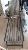 Used folding chaise lounge chair with brown striped fabric and metal frame, shown open and fully extended.