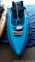 Overhead view of blue kayak with paddle and seatback showing overall condition