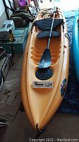 Top-down view of yellow kayak on floor with paddle across deck