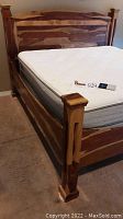 Front view of rustic wooden bed frame and Sleep Number mattress with remote control placed on top