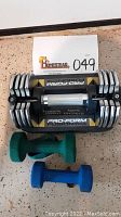 Pro-Form Fusion adjustable dumbbell with 5 lb green and 7 lb blue dumbbells visible below