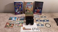 Full lot showing View-Master stereoscope, original box, reels, and three unopened Disney VHS videos lined up behind on lace tablecloth.