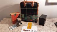 Thermos kit box standing upright with original bag visible behind. Bag has dark green and orange plaid pattern with tan leather handles and original labels.