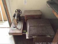 Antique radio with wooden body, antique sewing machine mounted on wood base, both on a black table.