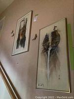Two vertical framed paintings hung on a wall, showing trees and waterfall scenes, each measuring 30 x 15 inches.