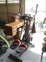 Front left three-quarter view of elliptical trainer showing foot pedals, stationary and moving handlebars, console