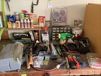 Wide view of garage workbench showing assorted chemicals, hand tools, and hardware bins.