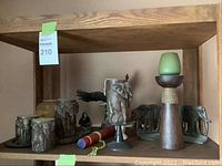 Shelf with mix of carved wooden animal figurines, metal elephant candle holder, and tall wooden candle holder with green candle