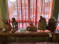 Full view of all five Native American themed decorative items on a wooden table under a red sheer curtain.