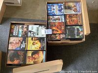 Two boxes filled with DVD cases showing various movie titles for sale.
