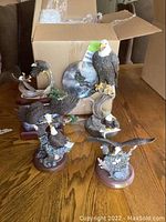 Group of five resin eagle sculptures on table in front of open box