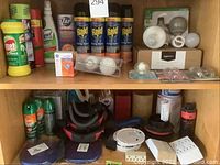 Wooden shelf with various insect sprays including Raid and OFF, Lysol disinfectant, Comet bleach cleaner, ZAP insect repellent, multiple electrical extension cords, sanding pads and connectors on bottom shelf.