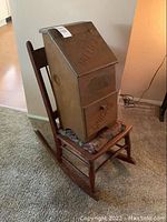 Rocking chair with floral cushion, on which sits a solid wood potatoes and onions storage bin with pegboard back and labeled compartments