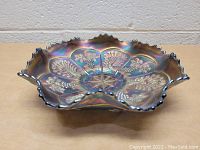 Angled side view of the vintage carnival glass bowl showing the iridescent colors and scalloped ruffled edge.