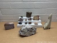 Wide shot of all the rocks arranged on a stepped white display and table showing variety in size, color, and texture