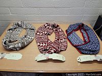 Front view of three infinity scarves laid flat on a cardboard surface showing different colors and patterns.