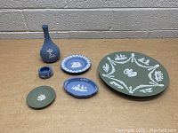Five assorted Wedgwood Jasperware pieces on a table including plates, dish, and vase.